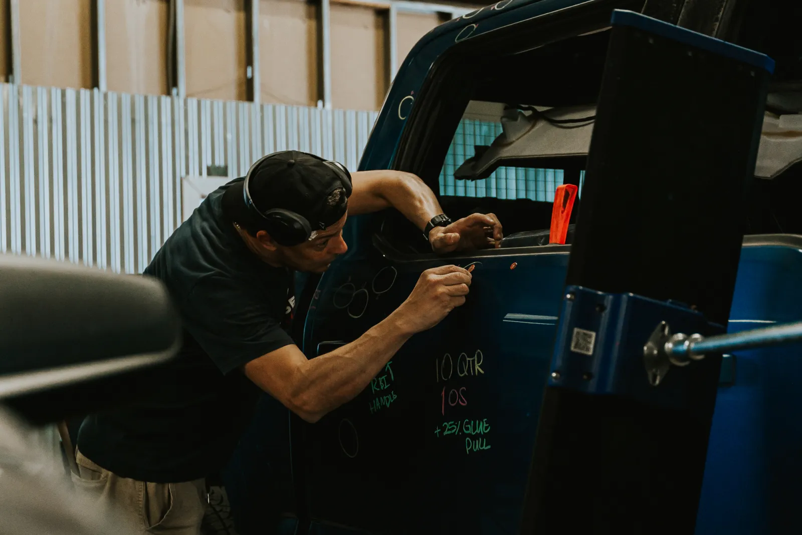 Certified PDR technician marking dents on a blue truck door panel — Lubbock, TX hail repair